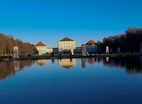 Ein weißes Barockschloß spiegelt sich im Wasser