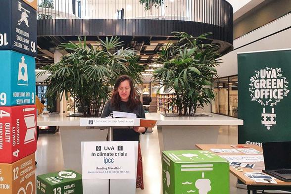An der Universität Amsterdam fand 2024 ebenfalls ein IPCC-Reading von Forschenden und Klimaaktivist*innen statt. Das Foto zeigt eine Frau mit einem Blatt in der Hand, von dem sie abliest. Sie steht in einem Gebäude der Universität Amsterdam. 
Bildquelle: Scientist Rebellion Niederlande