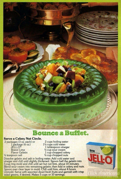 This lime Jell-O salad is in the shape of a ring. In the center looks to be lettuce nuts fruit, celery.