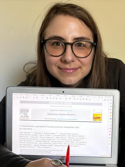 Nina Davtian (that's me!) at her work office, with the laptop screen showing the header of her co-authored article by Ochando et al. (in press) QSR (https://doi.org/10.1016/j.quascirev.2024.109025) and her pen showing where her name appears in the author list.