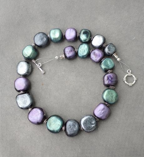 Handmade lampwork glass bead necklace in opaque black with added mica powder in silver, teal and purple.