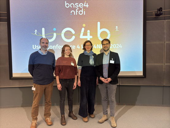 4-Personen in Front of the user base4nfdi conference logo