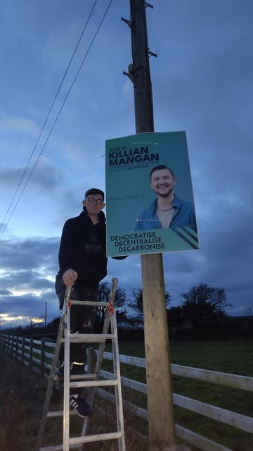 A photo of Jack standing on a ladder with a poster.