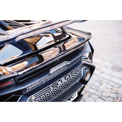 The picture shows the rear end of a black lamborghini supercar. You can see the reflection of the surrounding  environment on the coating.