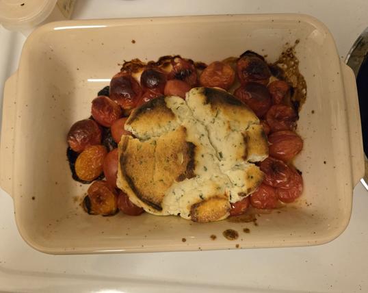 Roasted cherry tomatoes & baked Boursin cheese in a small cream ceramic dish that fits into a small toaster oven.