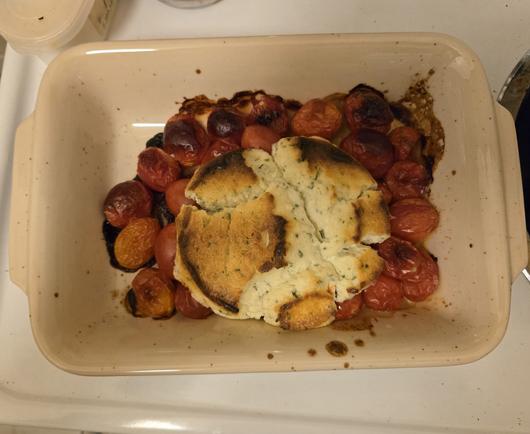 Roasted cherry tomatoes & baked Boursin cheese in a small cream ceramic dish that fits into a small toaster oven.