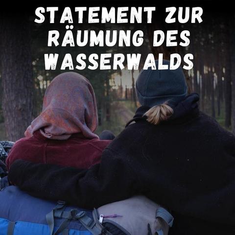 Das Foto zeigt zwei Personen, die mit dem Rücken zu/m/r Betrachter:In auf einen Waldweg schauen. Die linke Person hat ein Tuch um den Kopf gebunden, die Rechte eine dunkle Strickmütze auf. Beide sind in Fleece Jacken gekleidet im Vordergrund liegt ein Rucksack, an den sich die linke Person anlehnt. Die rechte Person hat den Arm um die linke gelegt. Über dem Foto ist der Text "Statement zur Räumung des Wasserwalds" zu lesen.