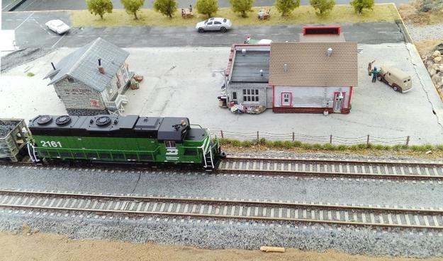 An N-scale Burlington Northern locomotive passes behind some houses on our T-TRAK layout.