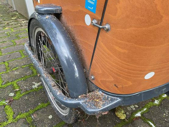 vorderrad eines lastenrades mit komplett verdrecktem rahmen