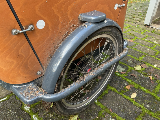 vorderrad eines lastenrades mit komplett verdrecktem rahmen