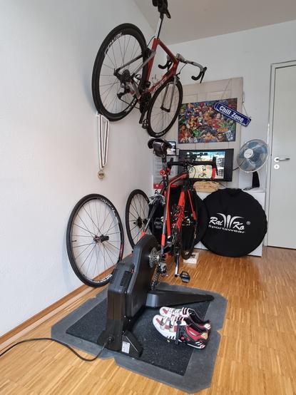Zimmer mit einem Rennrad auf einer Rolle montiert, ein zweites in einer Halterung an der Wand.