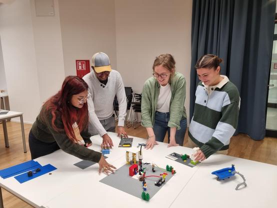 4 Personen stehen im einen Tisch und schauen auf ein Lego Modell