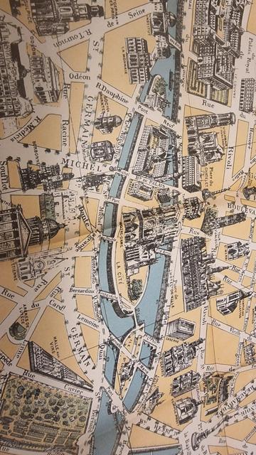 close up of an old map of Paris. Monuments are shown as sketches, And the streets are lined with small depictions of trees.