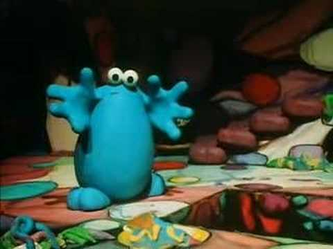 A screencap of the 1980s kid's TV series "Trapdoor" showing Berk, a blue plasticine blob creature, stood beside an open trapdoor looking a little bit concerned.