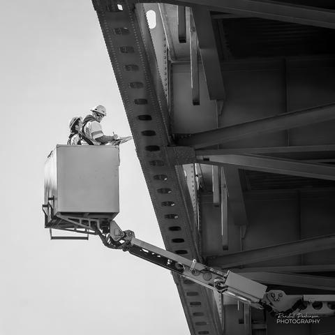 Two bridge inspections in a bucket inspection the steel members of a large river bridge.