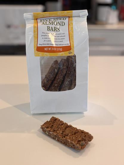 A bag of Trader Joe’s five seed almond bars with one piece laying in front of the bag