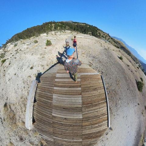 Photo of three people walking on a boardwalk near hot springs in Yellowstone National Park.