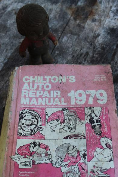 Closer up you can see this one book was for repairing every American made car from the years 1972 through 1979 & though it is a thick book it isn't  massive. The hand penciled illustrations that adorn the cover are featured throughout.

Standing behind is a 1970 Vinyl Doll originall promotional item from Campbell soup company. It appears as if someone liberally re-applied dirt to it annually since 1970.