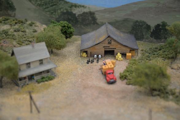 A small farm scene with hay bales set up outside an N-scale barn.