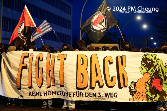 Das Hauptbanner der antifaschistischen Demonstration. Auf dem Banner steht "Fight Back. Keine Homezone für den 3. Weg". Darüber hinaus sind mehrere Fahnen mit dem "Antifaschistischen Aktion" Logo zu sehen.