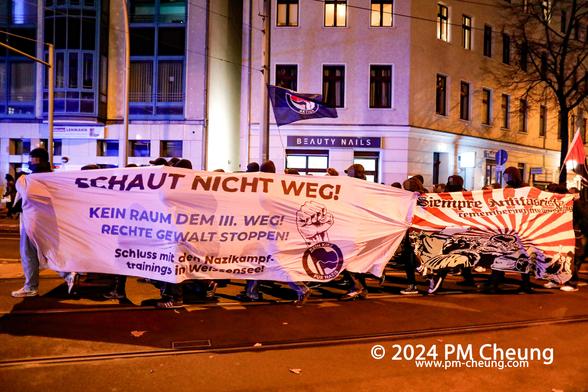 Die Demonstration erreicht den Antonplatz. Hier ist der Demonstrationszug mit zwei Banner zu sehen, auf dem einen steht "Schaut nicht weg! Kein Raum dem III. Weg! Rechte Gewalt stoppen! Schluss mit dem Nazikampftrainings in Weißensee!".