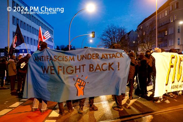 Bei der Auftaktkundgebung wird ein Banner mit der englischen Aufschrift "Antifascism under Attack. We fight back!" zu sehen. Hier geht es um die Kriminalisierung des Antifaschismus.