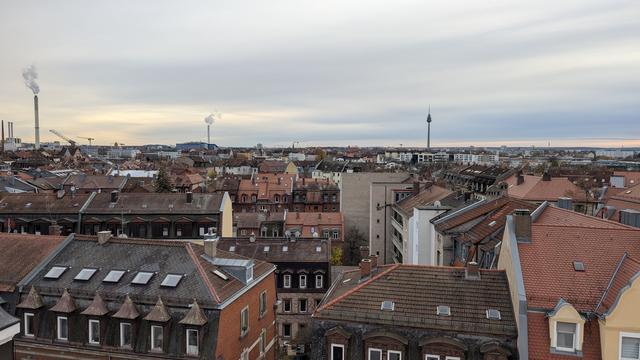 Blick über Nürnberg Richtung Süden. In der ferne sind mehrere Schornsteine und der Nürnberger Fernsehturm zu sehen.