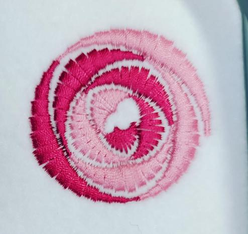 A stitched representation of the Glasgow Rose, designed by Charles and Margaret Rennie Mackintosh. Its stitched onto white felt, with two colours of pink thread.