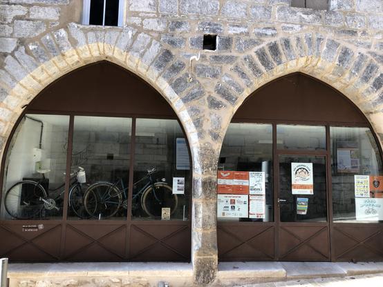 Façade de l’atelier vélo la Véloterie, avec deux arches en pierre et une large vitrine