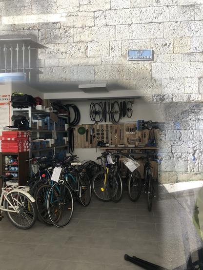 Intérieur de l’atelier prisa travers la vitrine (ce qui donne un effet bizarre à la photo. C’est bien rangé. Avec la réflexion on voit que nous sommes rue du Château du Roi.