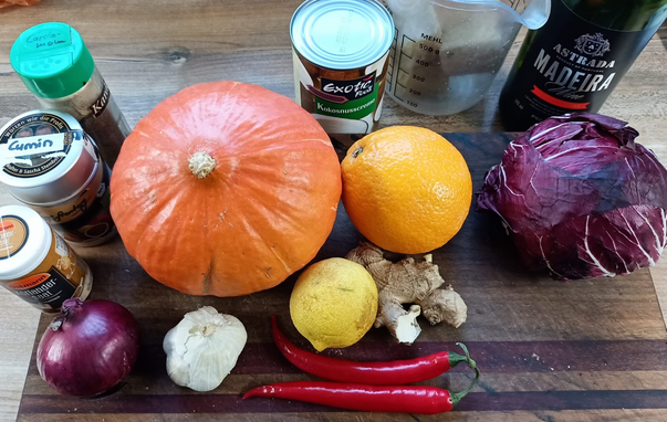 Auf einem Brett ein Hokkaidokürbis, Radicchio, Ingwer Knoblauch 2 rote Chili eine rote Zwiebel, eine Dose Kokoscreme, eine Flasche Madeira + die Gewürze