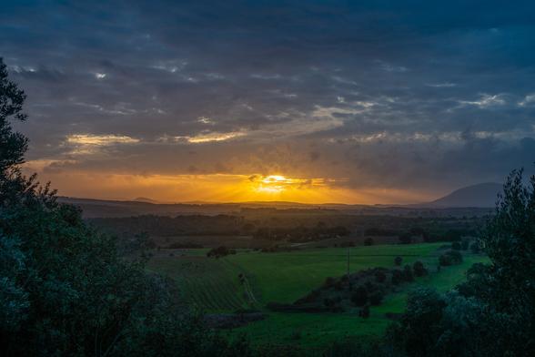 looking out from a hill out over the valley around Montejunto in the distance at sunset on a stormy evening