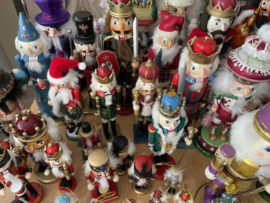 A table covered with nutcrackers of different sizes and colors, not an inch of the photo is free of nutcrackers.