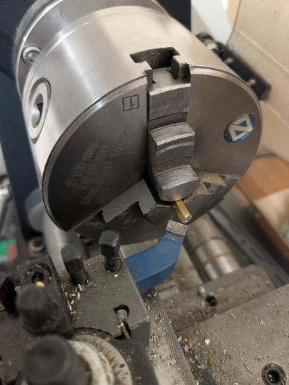 Sur le tour à métaux une petite colonne hexagonale en laiton de 30mm en cours d'usinage