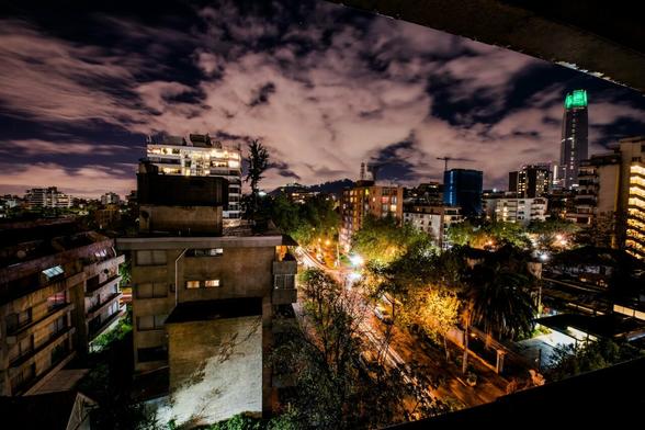 La vue d'un balcon à Santiago du Chili. Les lumière de la ville jouent avec l'architecture. Les nuages colorés de rose orangé amènent le contraste d'un paysage presque surréaliste.