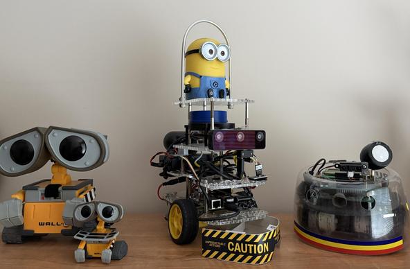 Shelf with WALL-E figures from 2023 Create3-WaLi robot, GoPi5Go-Dave robot (Minion Dave on top) built in 2018, Rug Warrior Pro robot built in year 2000.