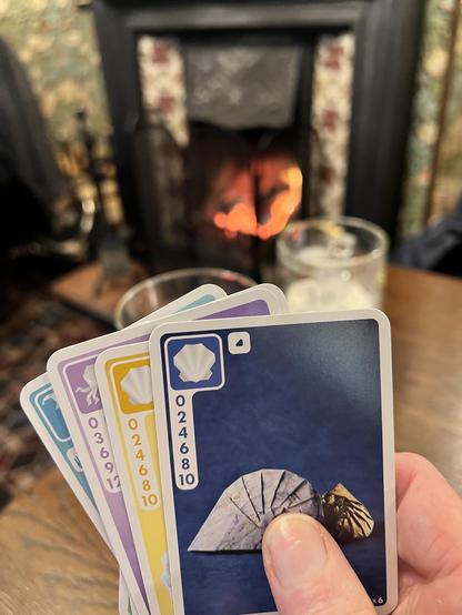 A hand of cards in Sea Salt and Paper. Pictured in front of two beers and a real fire.