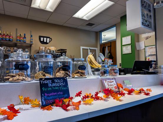 View of a cafe counter with jars of cookies on top and a ledge with decorative orange leaves