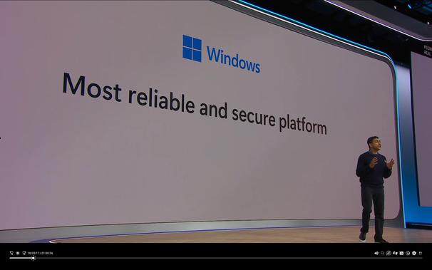 A screenshot of Microsoft's keynote, with a person in front of a giant screen that says "Windows, Most reliable and secure platform"
