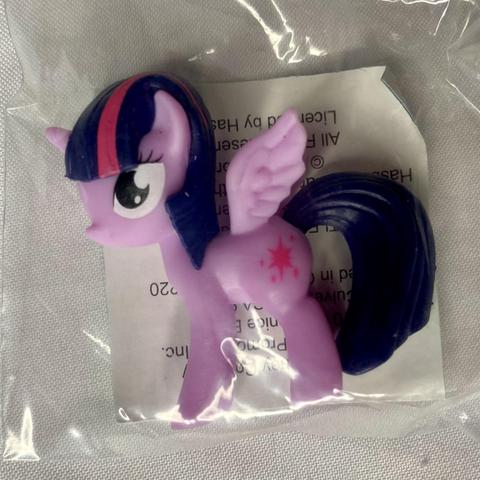A small plastic figure of a purple winged pony with dark hair and a star symbol on its side, enclosed in a clear plastic bag.