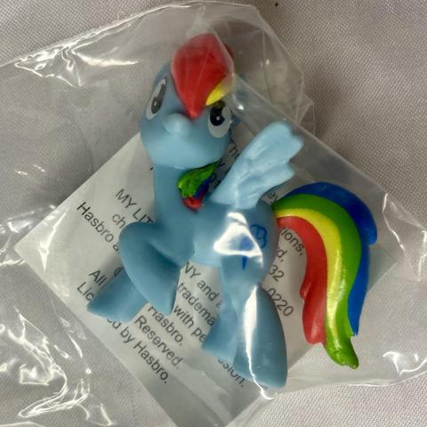 A small blue toy pony figurine with a rainbow mane and tail, enclosed in a plastic bag. The pony has wings and a cheerful expression.