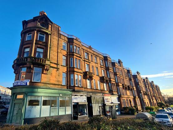 The long facade of an upmarket red sandstone Glasgow tenement.