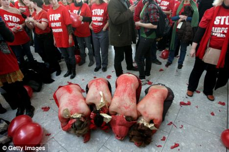 Young women decide to use red ochre body paint to say NO to Heathrow expansion. They are surrounded by protestors in red t-shirts