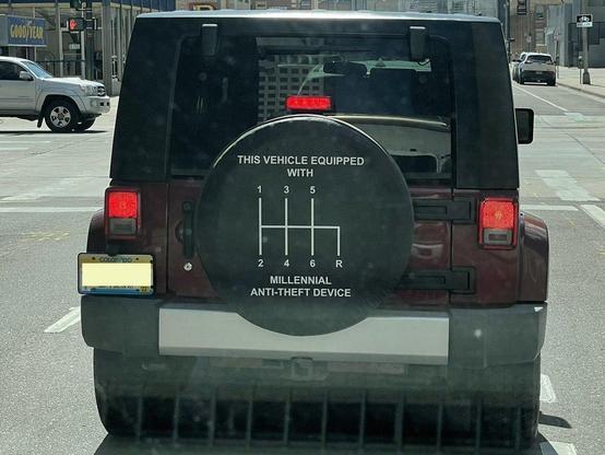 Back of a vehicle with tire cover reading:

This vehicle equipped with millennial anti-theft device.

It shows a manual 6-speed shift pattern.

Denver, 2022