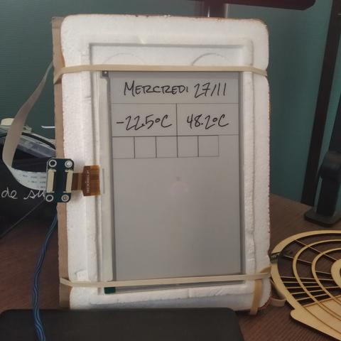 Picture of a 7" eink display.
On top, it displays today"s date in french "Mercredi 27/11".
Below the date, two temperatures "-22.5°C" and "48.2°C"