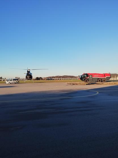 Helicopter hovering between follow-me and fire-fighters.