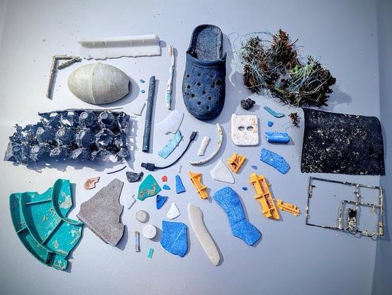 All of the big and little pieces of plastic I picked up on the beach, including a black croc, toothbrush, USB dongle, and a half of a fishing net buoy.