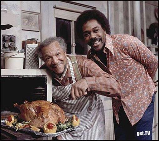 Fred Sanford and his son Lamont smiling and leaning over a Thanksgiving turkey with trimmings. Watch the 70s TV show Sanford and Son'. It's funny and  it has a Quincy Jones theme track (The Streetbeater), with next-level harmonica.