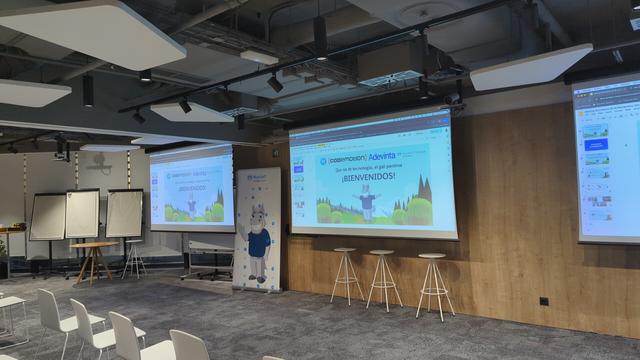 Conference room, it has three projectors with a presentation displayed onto it.