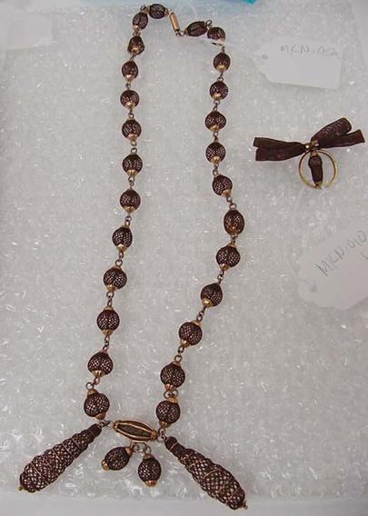 A chain of hairwork beads, ending with several hairwork pendants, and a hairwork brooch that looks like a bow with an acorn hanging in a ring to one side.